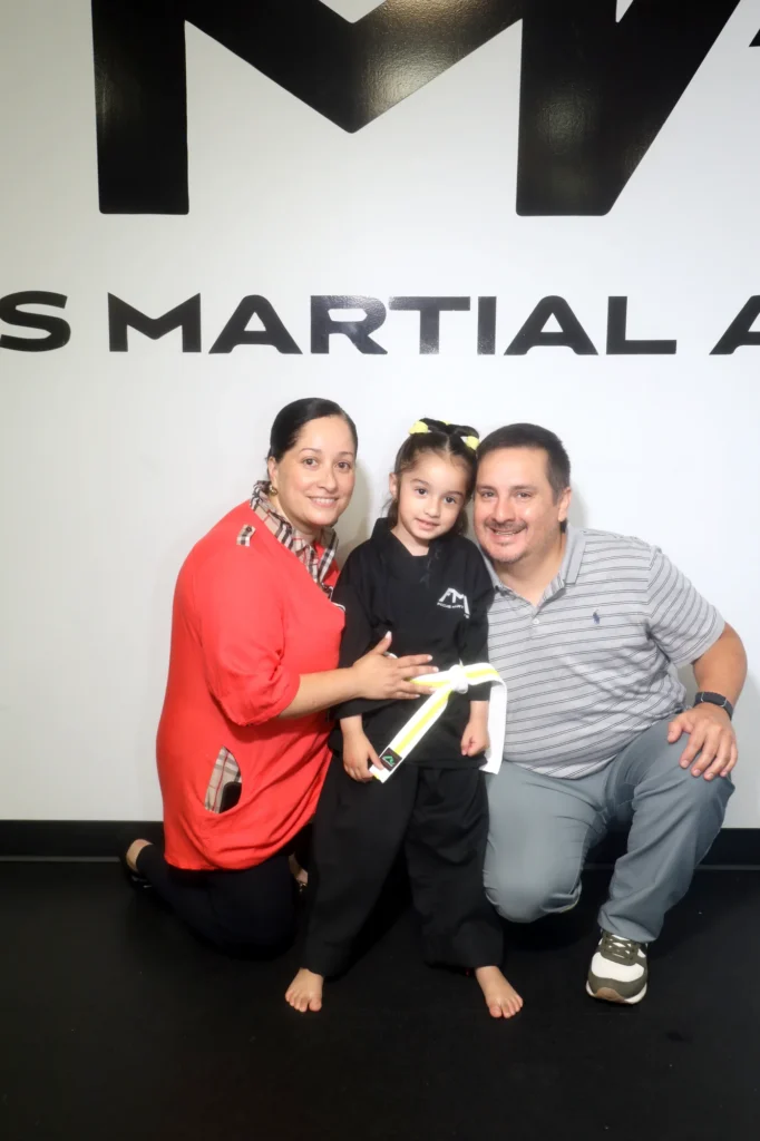 Focus Martial Arts Family posing with a young student holding a promotion