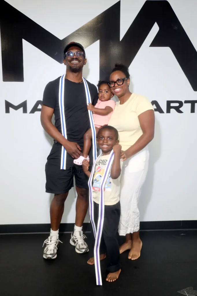 Family posing with two children wearing striped belts draped