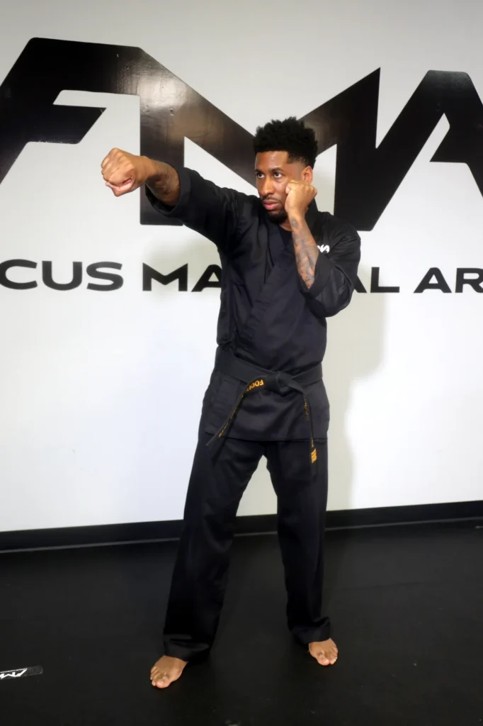 Focus Martial Arts instructor demonstrating a high side kick in a black FMA
