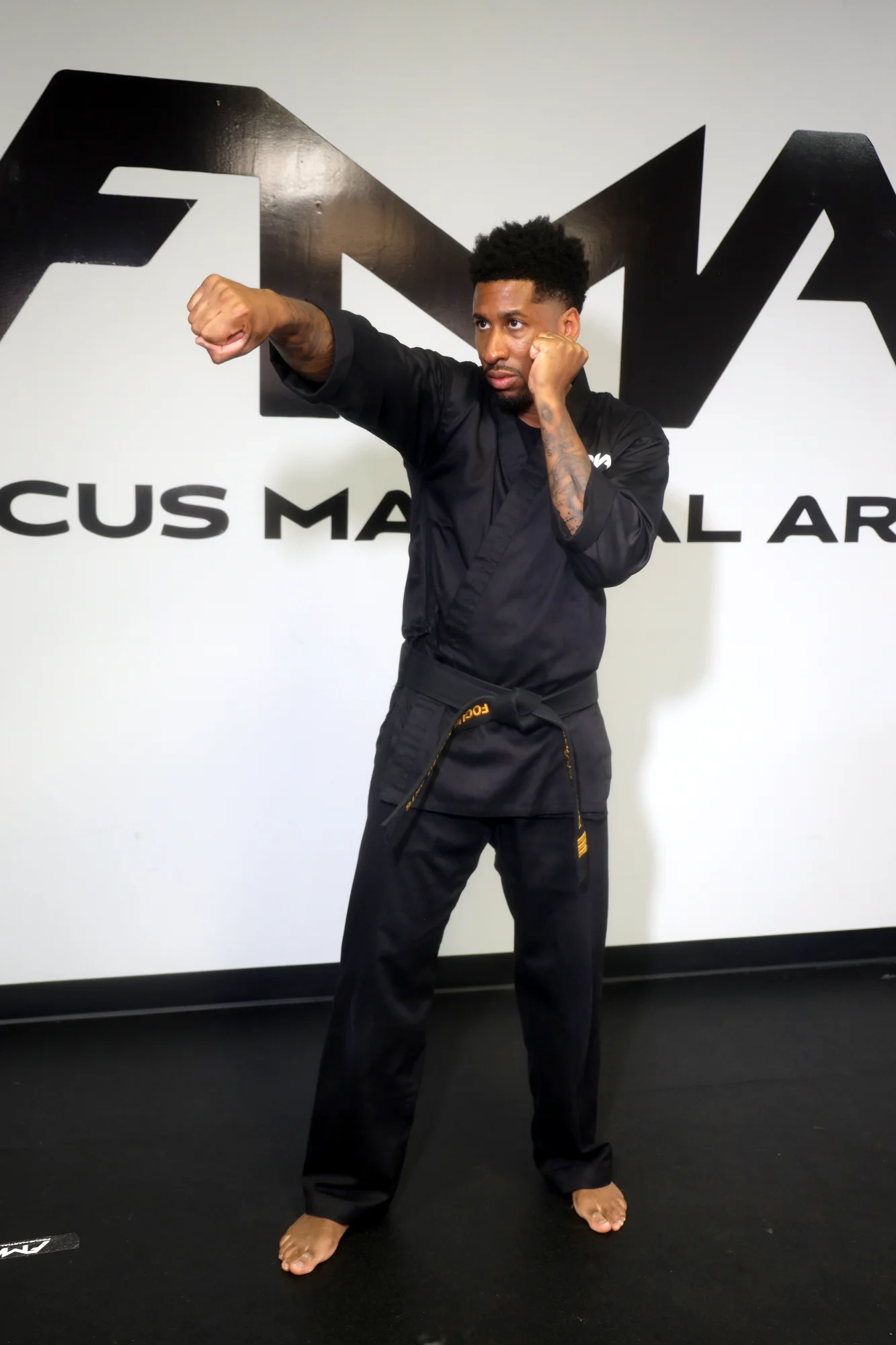 Focus Martial Arts instructor demonstrating a high side kick in a black FMA