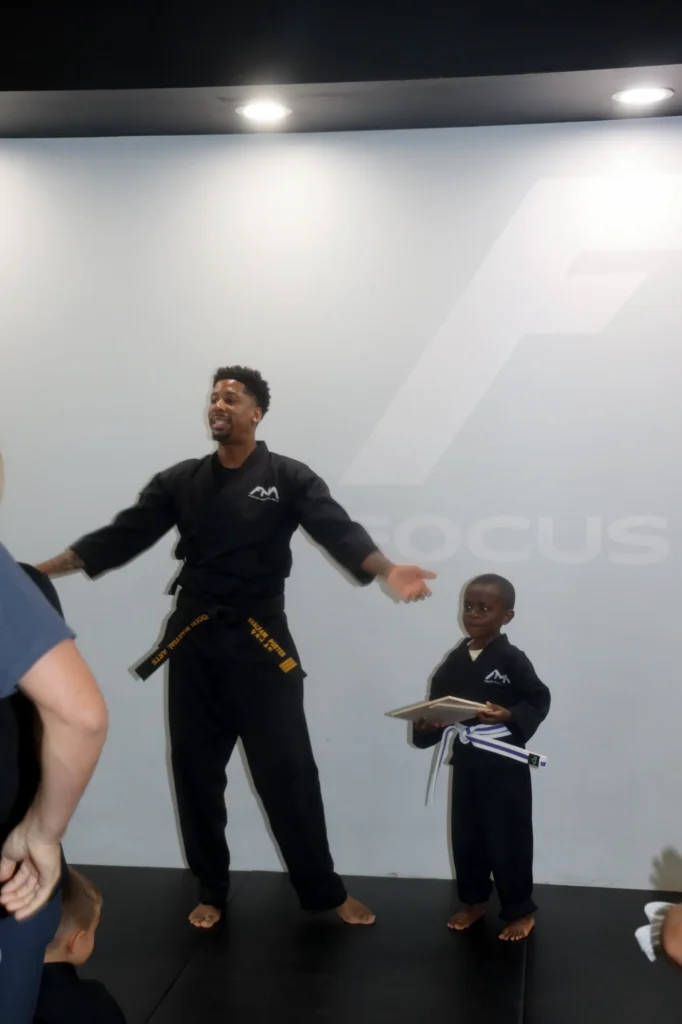 Focus Martial Arts instructor demonstrating a kick for a teen student holding a