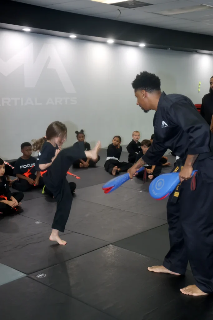 Focus Martial Arts instructor holding kick pads while young students practice