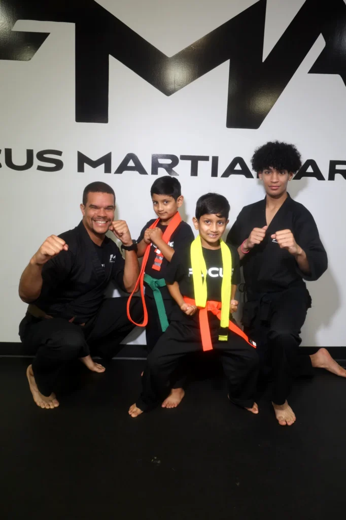 Focus Martial Arts instructor posing with teen students performing high kicks