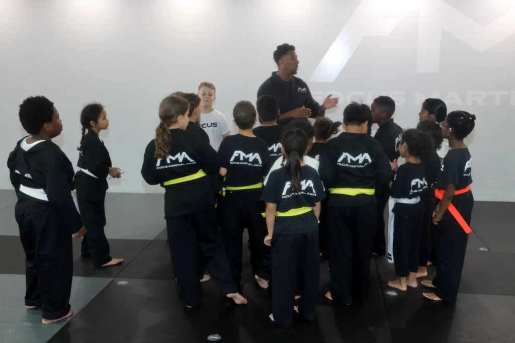 Focus Martial Arts instructor talking with a group of kids students standing