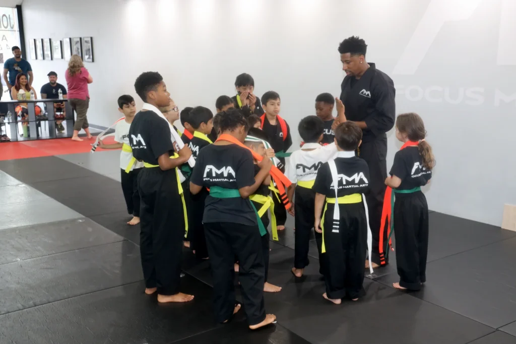 Focus Martial Arts instructor talking with a group of kids wearing colorful