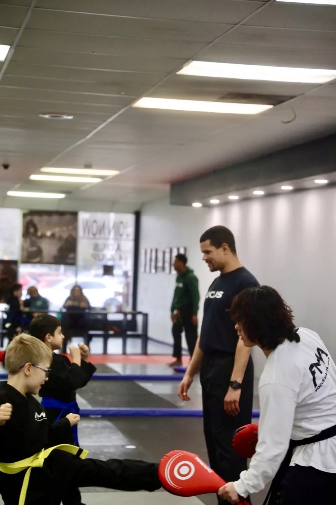 Focus Martial Arts instructors holding kick pads for kids students practicing